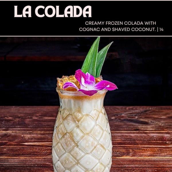 La Colada, a creamy frozen colada with cognac and shaved coconut, garnished with a purple orchid.