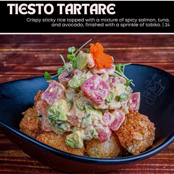 Tiesto Tartare with crispy sticky rice, spicy salmon, tuna, avocado, and tobiko in a black bowl.