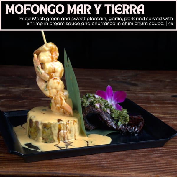 Mofongo Mar y Tierra with shrimp in cream sauce and churrasco in chimichurri sauce on a black plate.