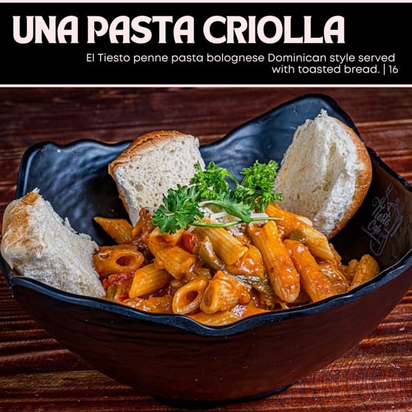 El Tiesto penne pasta bolognese, Dominican style, served with toasted bread in a black bowl.