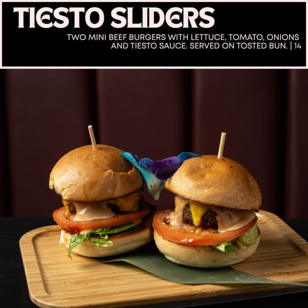 Two Tiesto Sliders, mini beef burgers with lettuce, tomato, onions, and Tiesto sauce on a wooden board.