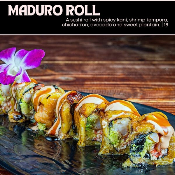 Maduro Roll sushi with spicy kani, shrimp tempura, chicharron, avocado, and sweet plantain, garnished with an orchid.
