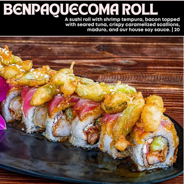 A Benpaquecoma sushi roll with shrimp tempura, seared tuna, scallions, and maduro on a black plate.