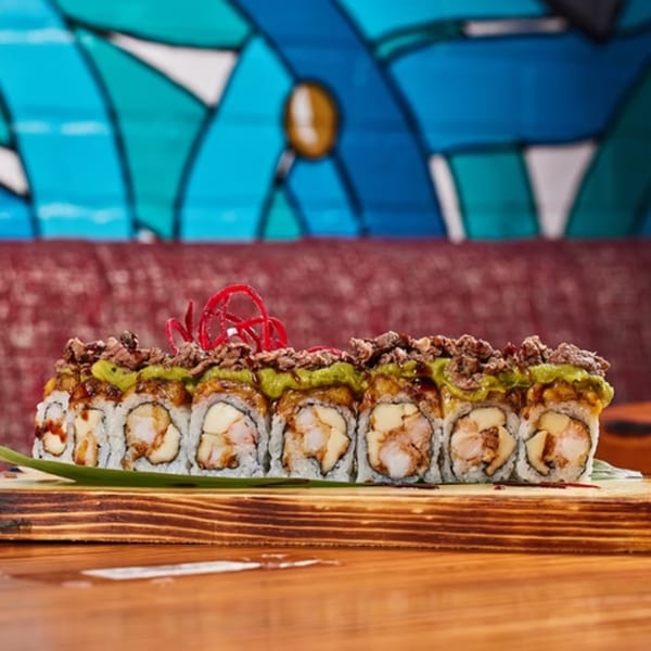 El Tiesto Cafe's sushi roll with shrimp, avocado, and beef on a wooden board.