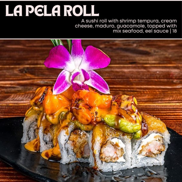 La Pela Roll with shrimp tempura, cream cheese, maduro, guacamole, mixed seafood, and eel sauce, garnished with an orchid.