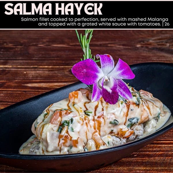 Salmon fillet with white sauce, tomatoes, and herbs, garnished with a purple orchid.