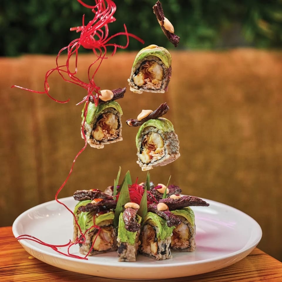 El Tiesto Cafe's sushi rolls with avocado, shrimp, and beef, garnished with red strings.